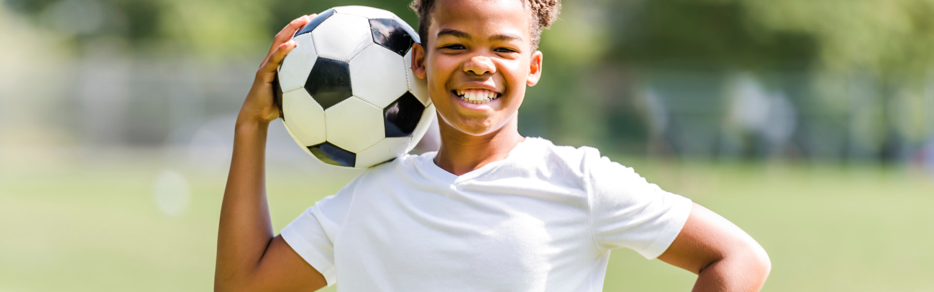 boy smiling while holding a ball