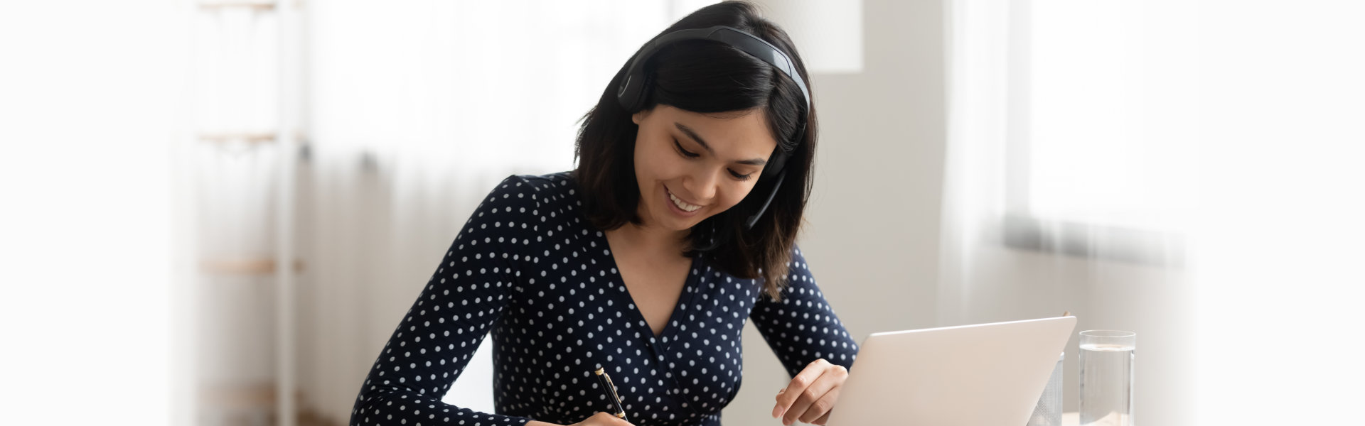 woman wearing headset listening and keeping notes on webinar